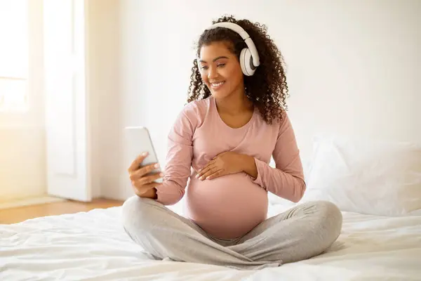 Mujer Negra Embarazada Feliz Disfrutando Música Usando Teléfonos Inteligentes Auriculares —  Fotos de Stock