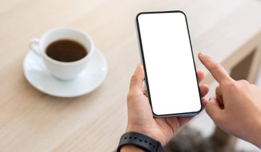 Kadın eli zımbırtıyı tutuyor, evde ya da kafede kahve içerken beyaz şablon ekranlı akıllı telefondan kayıyor, taklit alanı, mobil uygulama konsepti