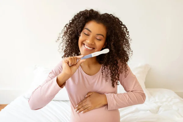 Beaming Μαύρη Μέλλουσα Μητέρα Κρατώντας Θετικό Τεστ Εγκυμοσύνης Και Αγκαλιάζοντας — Φωτογραφία Αρχείου