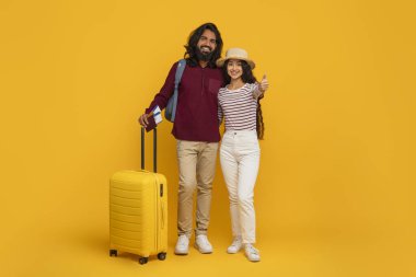 Mutlu genç Hintli eşlerin portresi, bavulları, pasaportları ve sarı arka planda seyahat biletleri olan neşeli Doğu çifti Stüdyoda, Tam Uzunlukta, Kopya Alanı