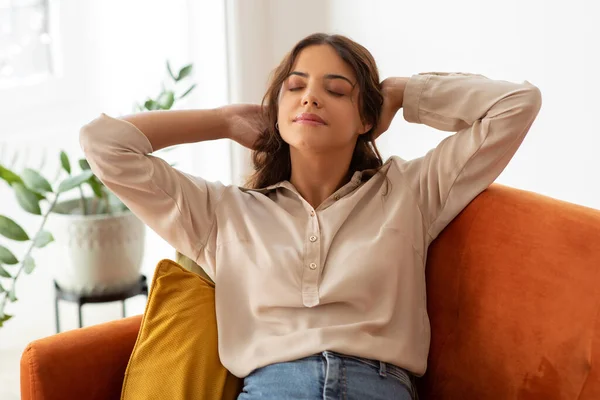 Domestic Comfort. Portrait Of Smiling Young Beautiful Woman Leaning Back On Couch, Dreamy Millennial Female Resting On Sofa, Relaxing With Closed Eyes And Hands Behind Back, Closeup Shot