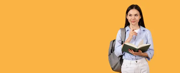 一个沉着的女学生 拿着书本 用铅笔摸着下巴 背着灰色的背包 在黄色的背景下看空旷的空间 — 图库照片