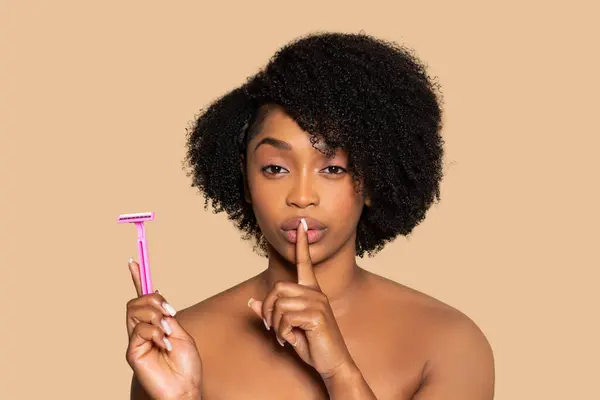 Zabawna Afroamerykanka Trzymająca Palec Ustach Różową Brzytwę Drugiej Ręce Wskazując — Zdjęcie stockowe