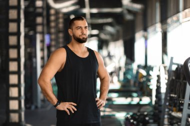 Antrenman motivasyonu. Spor salonunda ayakta duran kaslı erkek, kendine güvenen atlet, modern spor kulübünde eğitime hazır bir şekilde spor yapıyor. Fitness ve Spor Konsepti