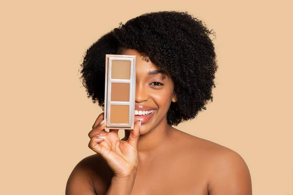 满脸笑容的非洲裔美国女人 卷曲的头发在她的脸旁边呈现着隐蔽性的调色板 在米色的背景下展现出不同的妆容 — 图库照片