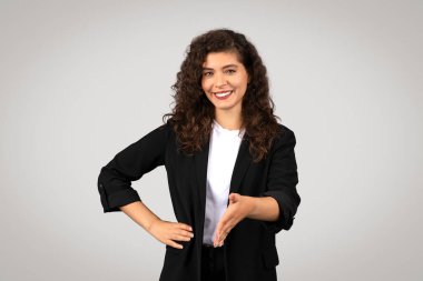 Gülümseyen iş kadını elini uzatıyor. Davetkar bir şekilde tokalaşmaya, samimi duruşuna ve samimi gülüşüne. Dostluk ve olumlu bağlardan bahsediyor.