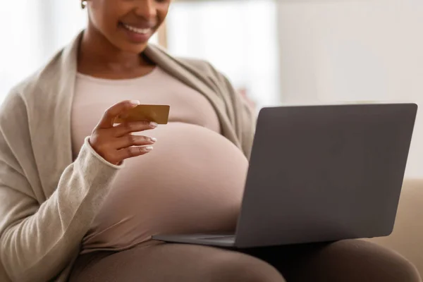 赤ちゃんのためにオンラインショッピングをする黒人の妊婦の母親のクロップは コンピュータとクレジットカードを使用して 自宅のソファーに座って 空のスペース アフリカ系アメリカ人女性がオンラインで購入することを期待 — ストック写真
