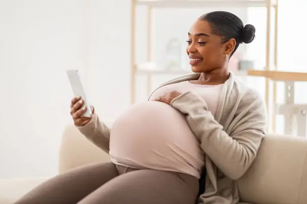 Sonriendo Mujer Afroamericana Embarazada Navegando Por Internet Teléfono Inteligente Casa —  Fotos de Stock