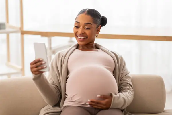 Χαρούμενη Μαύρη Έγκυος Γυναίκα Που Χρησιμοποιεί Smartphone Ενώ Χαλαρώνει Στον — Φωτογραφία Αρχείου
