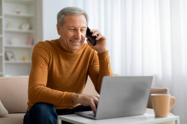 İş konsepti iletişimi. Ofiste dizüstü bilgisayarda çalışan, iş ortağıyla telefon görüşmesi yapan, bilgisayar ekranına bakan, toplantı ayarlayan kıdemli girişimci.