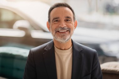 Hoş geldin yakışıklı, sakallı, gözlüklü, ceketli ve balıkçı yaka yakalı beyaz bir adam kameraya içten bir şekilde gülümsüyor.