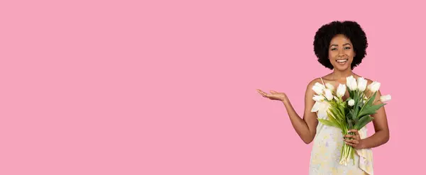 快乐的年轻非洲裔美国女人 一头黑发 一只手拿着一束漂亮的白色郁金香 一只手拿着粉红的背景 — 图库照片