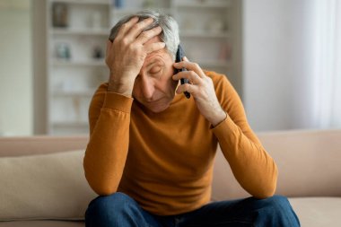 Oturma odasındaki koltukta oturan, evde telefonla konuşan, kötü haber duyan, dokunan, yakın çekim yapan, uzayı kopyalayan Avrupalı gri saçlı kıdemli adam.