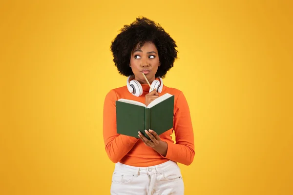 Młoda Kontemplacyjna Afroamerykanka Afro Włosami Nosząca Słuchawki Pomarańczowy Sweter Białe — Zdjęcie stockowe