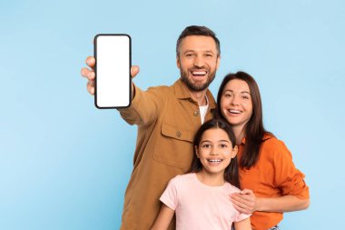 Mutlu aile pozu verirken, baba elinde boş ekranlı akıllı telefon, reklam uygulamaları ve internet içeriği için hazır, mavi arka planda karısıyla kızına sarılıyor. Model