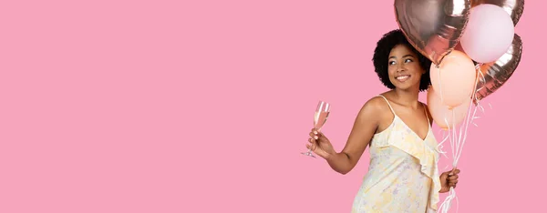 快乐的千年非洲裔美国女人 拿着气球和一杯闪闪发光的葡萄酒 微笑着向上看 背景是粉红的庆祝活动 工作室 — 图库照片