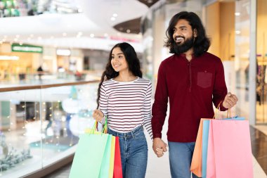 Genç Hintli eşler kağıt alışverişi yapıyor dükkan vitrinlerine bakıyor, hafta sonları hipermarkette birlikte yürüyorlar. Mutlu Doğu Müşterileri Hafta Sonu AVM 'de Eğleniyor. Büyük Satışlar