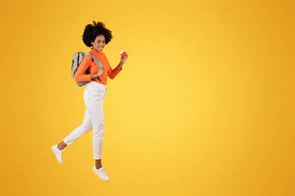 Energiczna Afroamerykanka Kręconymi Włosami Ubrana Pomarańczową Koszulę Białe Dżinsy Tenisówki — Zdjęcie stockowe