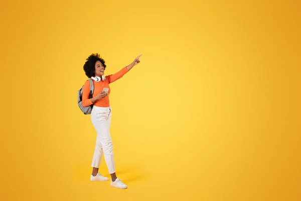 Radosna Afroamerykanka Kręconymi Włosami Wskazująca Podnieceniem Trzymająca Telefon Nosząca Pomarańczowy — Zdjęcie stockowe