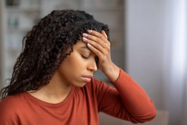 Evde baş ağrısı çeken, alnına dokunan, binlerce yıllık Afro-Amerikan kadınının somurtması, şiddetli migren veya ateş belirtileri, yakın çekim.