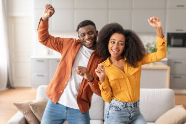 Romantik anlar. Eğlenmek için dans eden neşeli siyah çift, erkek arkadaş ve kız arkadaş evlerinde mutluluğu paylaşıyorlar, komik hareketler yapıyorlar ve gülümsüyorlar.