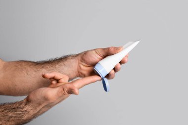 Erkekler İçin Cilt Bakımı. İnsanın parmaklarına besleyici krem sürmesi, nemlendirici losyonla tüp tutması, kendine özen göstermesi, Gri Stüdyo Geçmişi