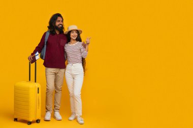 Sırt çantası ve sarı bavul taşıyan neşeli Hintli kadın ve erkek. Pasaport ve uçuş biletleri var. Sarı arka planda fotokopi alanını gösteren turistler.