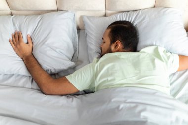 Yanındaki boş yastığa dokunarak, büyük rahat yatağında pijamalarıyla uyuyan, barışçıl, Afro-Amerikalı genç adamın en iyi görüntüsü. Bekar olmak, yalnız yaşam tarzı konsepti