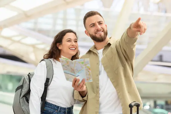 旅行コンセプト 新しい国に到着した後 空港ビル近くに立っているハッピーヤングカップル 陽気なミレニアルマンと女性の旅行ルートを計画 マンポイントアウェイ — ストック写真