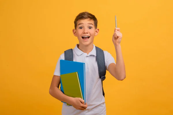 观念概念 兴奋的少男学生 背着背包和笔记本 用铅笔指向上方 男孩有灵感的时刻 站在黄色的工作室背景下 复制空间 — 图库照片