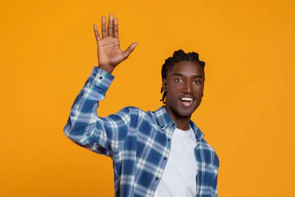 Hello. Portrait Of Friendly Young African American Guy Waving Hand At Camera, Cheerful Black Millennial Man Greeting Somebody While Standing Isolated On Yellow Studio Background, Free Space