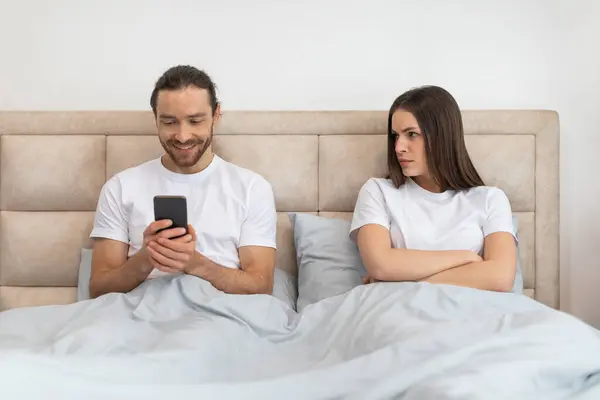 Mężczyzna Jest Szczęśliwie Zaangażowany Swój Smartfon Podczas Gdy Kobieta Obok — Zdjęcie stockowe