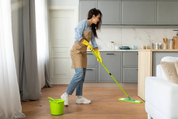 Focused Young Woman Casual Clothes Apron Diligently Mopping Wooden Floor — Stock Photo, Image
