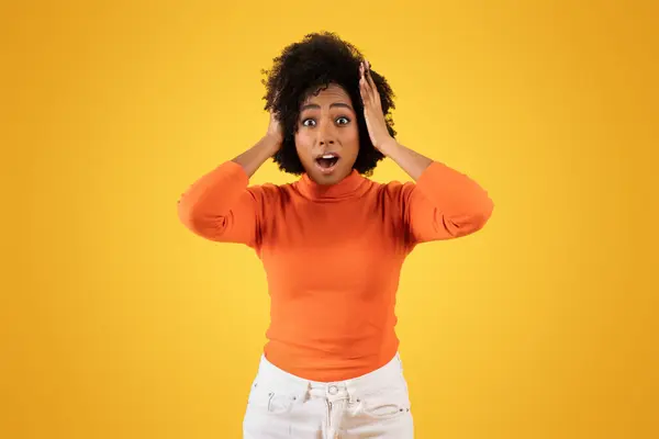 Zaskoczona Młoda Afroamerykanka Kręconymi Włosami Ubrana Pomarańczowy Sweter Białe Spodnie — Zdjęcie stockowe