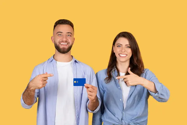 Gülümseyen Genç Çift Güven Içinde Mavi Kredi Kartını Işaret Ederek — Stok fotoğraf