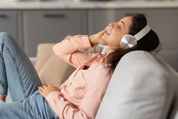 Mujer Radiante Descansando Sofá Perdida Música Con Auriculares Blancos Rostro — Foto de Stock