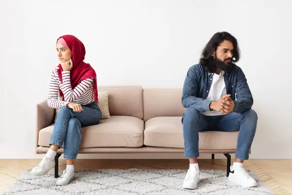 関係の危機 若いイスラム教徒の夫と妻は議論の後 カウチに戻って座っているグランピーのアラビアの配偶者 家庭用クォーレルの後に結婚したカップル怒っている 自由なスペース — ストック写真