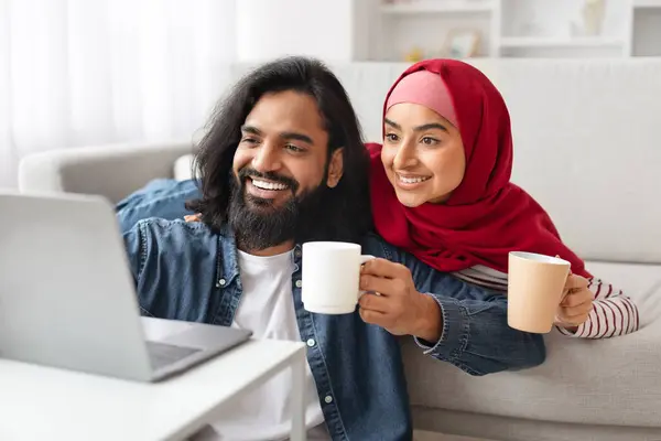 Ευτυχισμένο Μουσουλμανικό Ζευγάρι Φορητό Υπολογιστή Και Καφέ Χαλαρώνοντας Στο Σαλόνι — Φωτογραφία Αρχείου