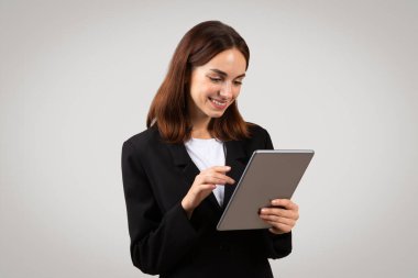 Binlerce yıllık özenli Avrupalı iş kadını elinde tuttuğu bir tablete odaklanmış durumda. Bu tablet modern profesyonellerin teknolojiye ve stüdyoya olan güvenini yansıtıyor.