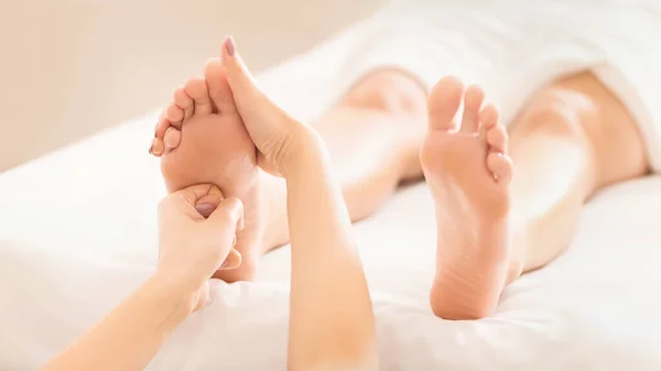 Foot massage. Woman relaxing at spa salon, reflexology treatment