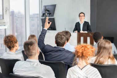 İş adamı seminerde el kaldırıyor, konuşması sırasında konuşacağı sorular var.