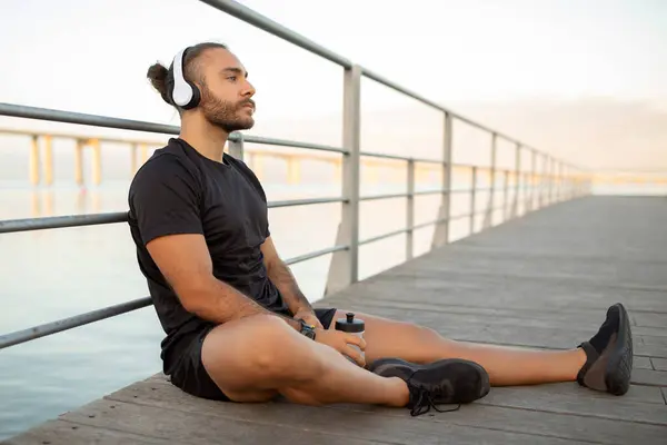 Millennial Athlete Guy Headphones Fitwear Sits Pier Enjoying Relaxing Break — Stock Photo, Image