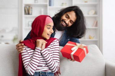 Romantik sürpriz. Arap kocasını seven, evinde mutlu Müslüman karısına hediye veren, onu doğum günü ya da yıldönümü ile selamlayan ve arkadan sarılarak sevinçle bağıran bir kadın.