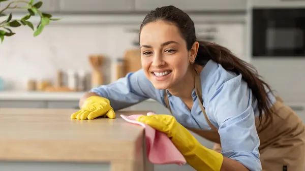 Mavi Gömlekli Sarı Eldivenli Gülümseyen Genç Bir Kadın Mutfak Masasını — Stok fotoğraf