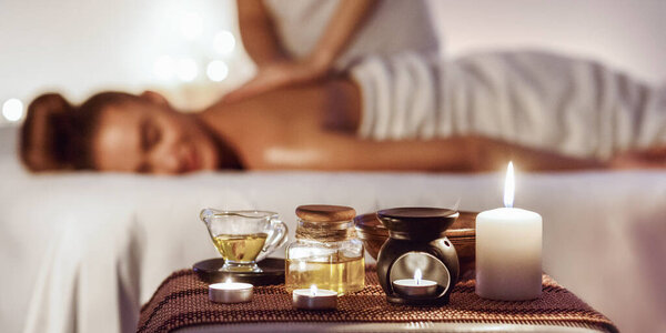 Aroma spa. Woman enjoying massage in luxury spa with candle on foreground