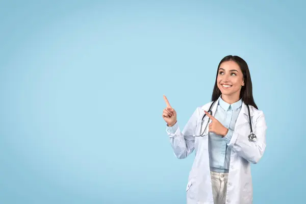 Радісна Жінка Лікар Вказує Вгору Вільний Простір Обома Руками Демонструючи — стокове фото