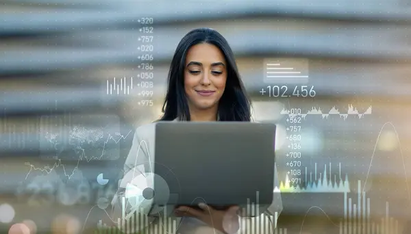 ダイナミックな財務チャートとデータ分析でオーバーレイされたノートパソコンを使用している自信のある若いプロの女性は 現代のマルチタスクビジネスマンを表しています 成功したビジネス — ストック写真