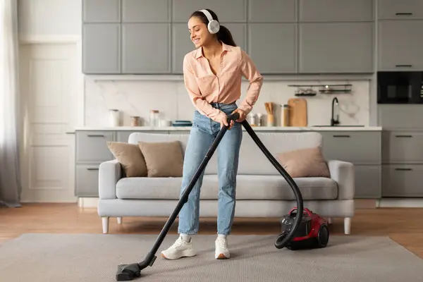 Contented Woman Wearing Headphones Enjoys Vacuuming Tidy Room Modern Red — Stock Photo, Image