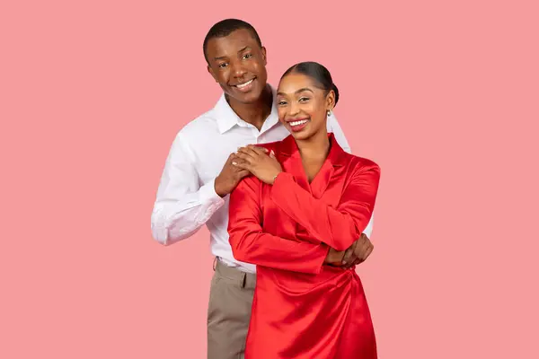 スタイリッシュな服装の陽気な若い黒いカップルは 活気に満ちたピンクの背景に対して一緒に楽しい瞬間を抱き 共有し ポジティブさを放射します — ストック写真