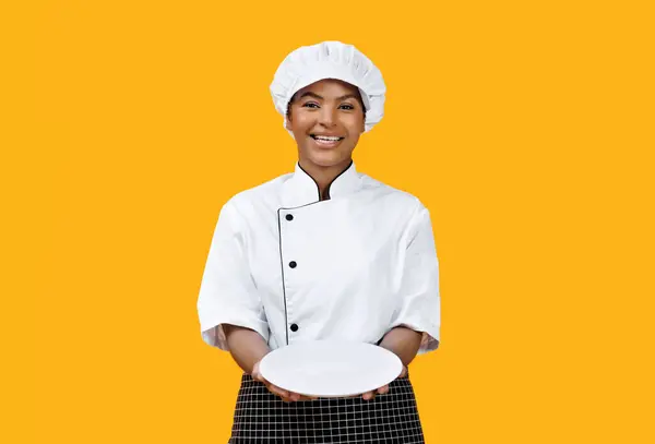 Cheerful Black Female Chef Proudly Presenting Empty White Plate Camera — Stock Photo, Image